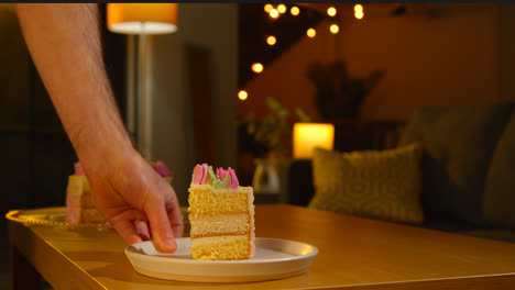 Person,-Die-Ein-Stück-Partykuchen-Zum-Geburtstag-Mit-Zuckerguss-Dekoriert-Auf-Den-Tisch-Zu-Hause-Legt